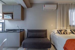 A compact room with a kitchenette, a bed with decorative pillows, and a window with sheer curtains. - Wbe710 in S o Paulo (São Paulo)