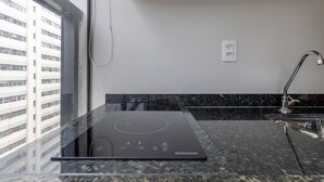 A modern kitchen with a built-in induction cooktop, a stainless steel faucet, and a black granite countertop. - Wbe710 in S o Paulo (São Paulo)