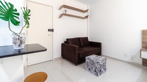 A modern living room with a brown sofa, a patterned ottoman, a glass vase with plants, and wooden shelves. - Av0905 in S o Paulo (São Paulo)