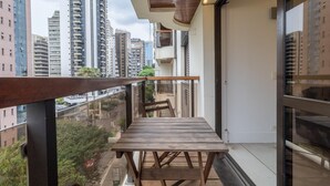 A balcony with a wooden table and chairs, overlooking a cityscape with tall buildings. - Haddock 166 in S o Paulo (São Paulo)