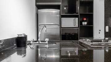 Uma cozinha moderna com frigorífico em aço inoxidável, máquina de café e pia com torneira.