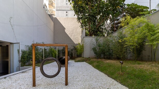A courtyard with a tire swing, gravel ground, and a building in the background. - Freicaneca 215 in S o Paulo (São Paulo)