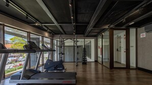 Ein Fitnessstudio mit Laufbändern, Kraftgeräten und einer Spiegelwand.
