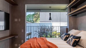 Ein modernes Schlafzimmer mit einem großen Bett, einem Balkon mit Sitzgelegenheiten und Blick ins Freie.