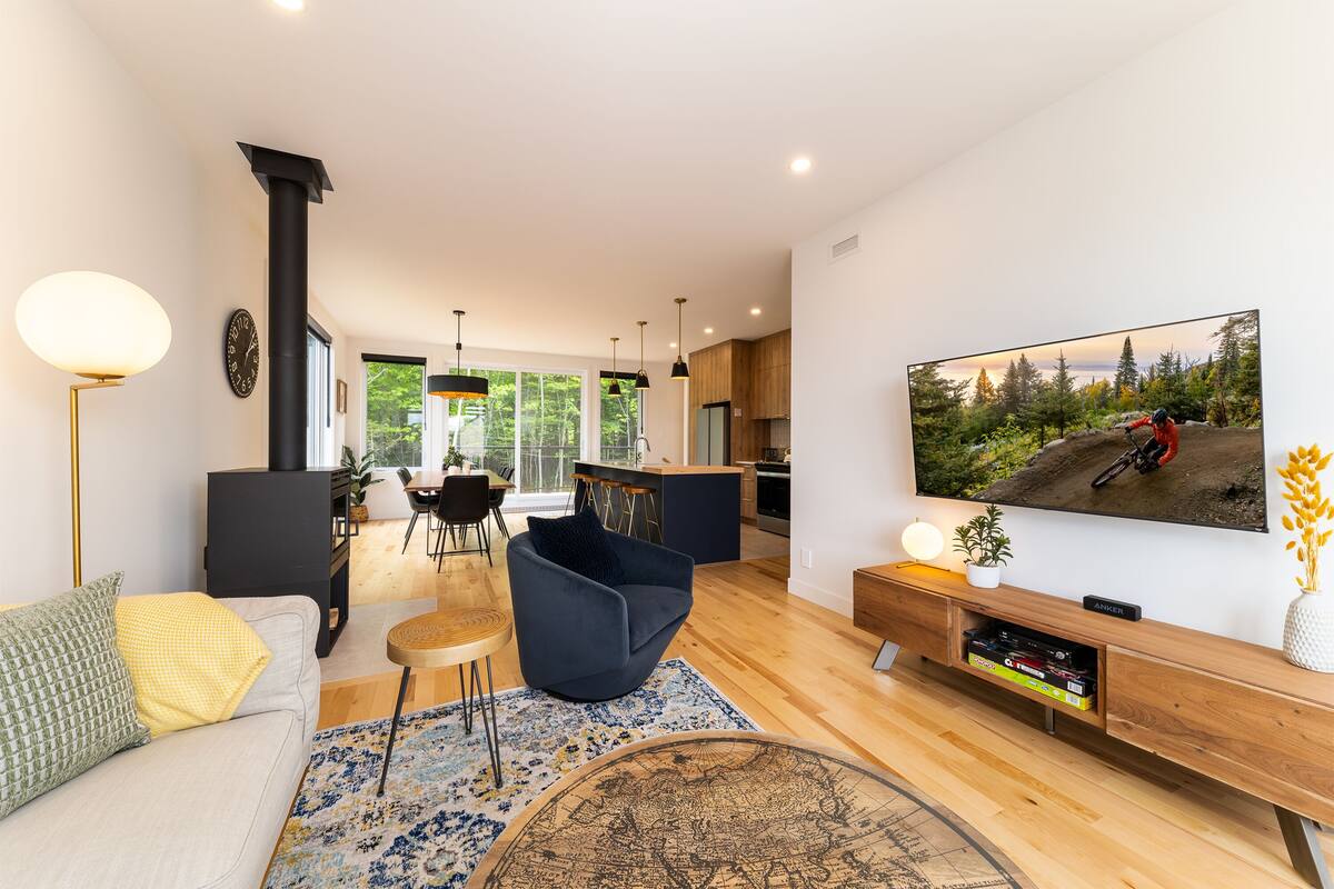 Un salon moderne avec un canapé, une table basse, un téléviseur et une cheminée.