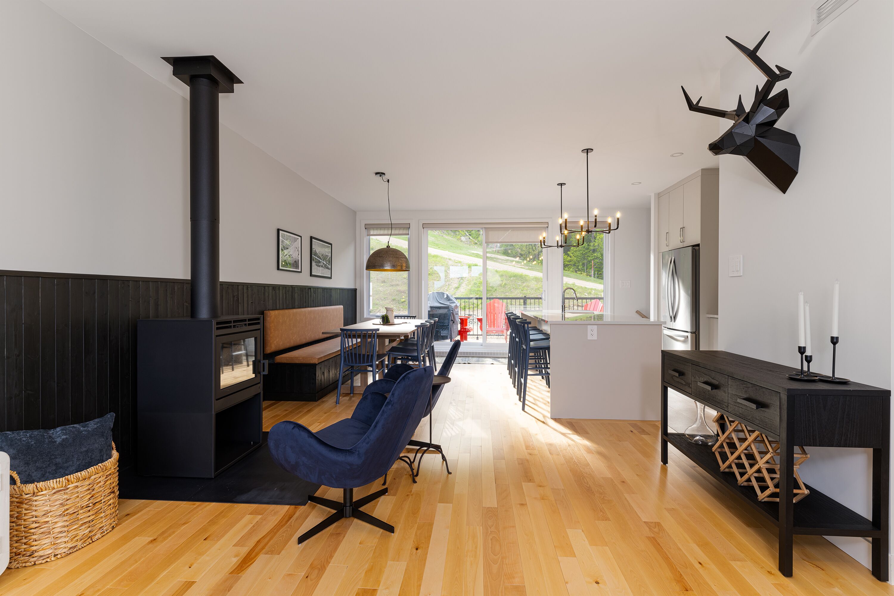 A modern kitchen with a central island, wooden flooring, and a large window providing a view of the outdoors.