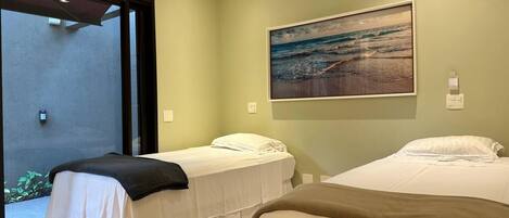 A hotel room with two beds, a large window, and a painting of a beach scene.