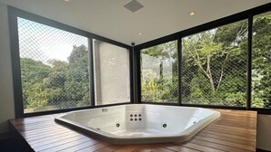 Ein modernes Badezimmer mit freistehender Badewanne, großen Fenstern und einem Fischgrätparkett.