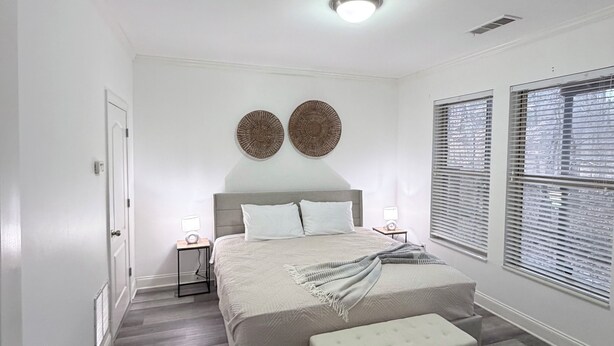 A bedroom with a bed, bedside tables, a bench, and a window with blinds. - Comfortable private suite in Buford North Atlanta (Buford)