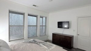 A bedroom with a bed, a dresser, a TV on the wall, and three windows with blinds. - Comfortable private suite in Buford North Atlanta (Buford)