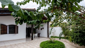 A courtyard with a tiled floor, a round garden bed, and a dining area with chairs and a table. - Villagio Santa Mônica (Caraguatatuba)