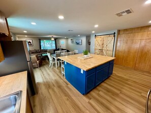 Una cocina moderna con una isla central, armarios de madera y una zona de comedor con sillas y una mesa.