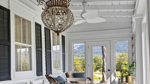 A covered porch with a dining table and chairs, a chandelier, and a view of the outdoors. -  Sparkle on the Rocks is a Sanctuary of Comfort and Artistic Inspiration (Wallingford)