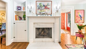 A room with a fireplace, bookshelves, a door, and a painting. -  Sparkle on the Rocks is a Sanctuary of Comfort and Artistic Inspiration (Wallingford)
