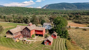 A large red barn with a white garage, a smaller red barn, and a white house with a red roof in a rural setting. -  Sparkle on the Rocks is a Sanctuary of Comfort and Artistic Inspiration (Wallingford)