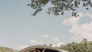 A small, single-story building with a curved roof and a sign that reads "GLAMPING RETRO." - The Turner Unit 1 - Glamping Retro (Erwin)