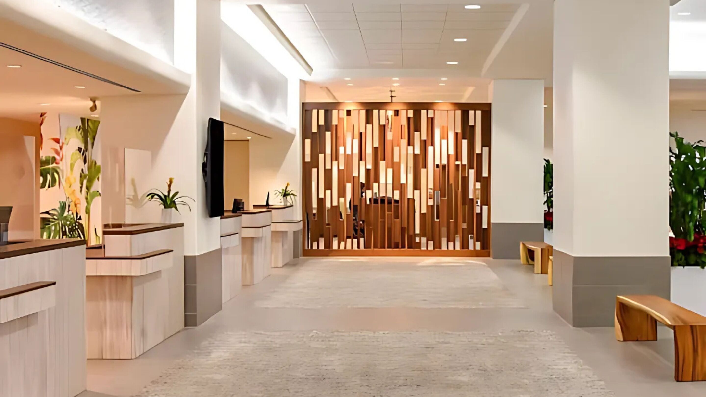 A modern reception area with a central wooden partition, multiple reception desks, and a bench.