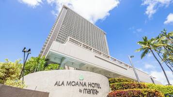 A tall hotel building with a modern design, featuring a prominent entrance and a sign reading "ALA MOANA HOTEL by mantra".