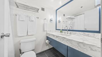 A modern bathroom with a white toilet, a marble sink, and a large mirror.