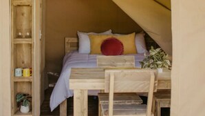 Ein gemütliches Zelt mit einem Bett, Holzmöbeln und einem Regal mit Gegenständen.