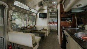 Ein kompaktes Wohnmobil-Interieur mit einer Küchenzeile, einer Essecke und einer kleinen Wohnfläche.