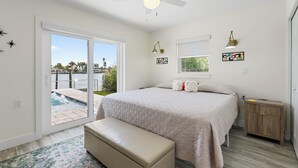 A bedroom with a bed, a bench, a nightstand, and a ceiling fan. - Waterfront! 1BR with private pool! 6 min. walk to the beach! (Treasure Island)