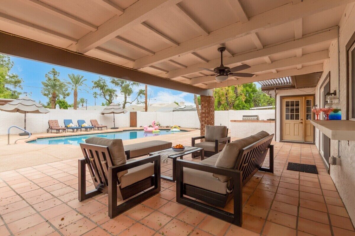 Une terrasse extérieure avec une piscine, des chaises longues et un espace bar.