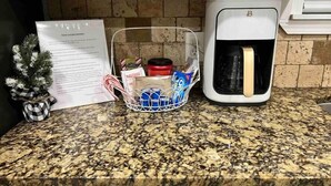 A kitchen counter with a coffee maker, a basket of snacks, and a small potted plant. - Sunset Melody - pet friendly  (Amarillo)