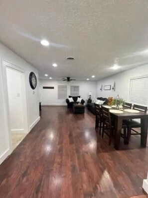 A spacious living room with hardwood flooring, a dining area with a table and chairs, and a ceiling fan. - Sunset Melody - pet friendly  (Amarillo)