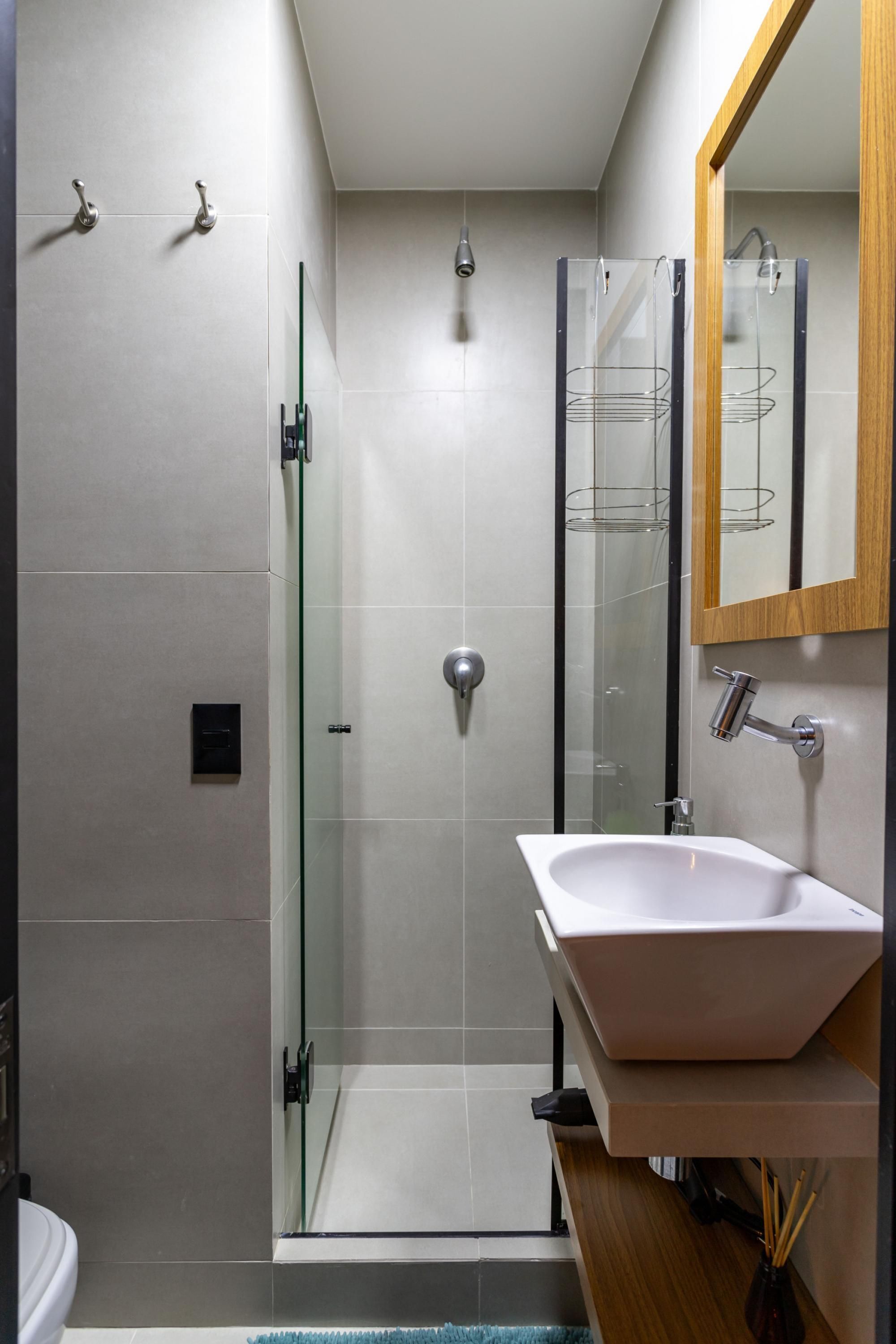 A modern bathroom with a glass-enclosed shower, a white sink, and a wooden vanity.