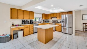 A modern kitchen with wooden cabinets, a central island, stainless steel appliances, and a bright, well-lit space. - Perfect for Families, Friends and Budget of all Sizes! Great Deal! Heated Pool! (Cape Coral)