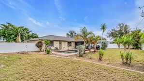 A residential house with a swimming pool, a lawn, and various plants. - Perfect for Families, Friends and Budget of all Sizes! Great Deal! Heated Pool! (Cape Coral)