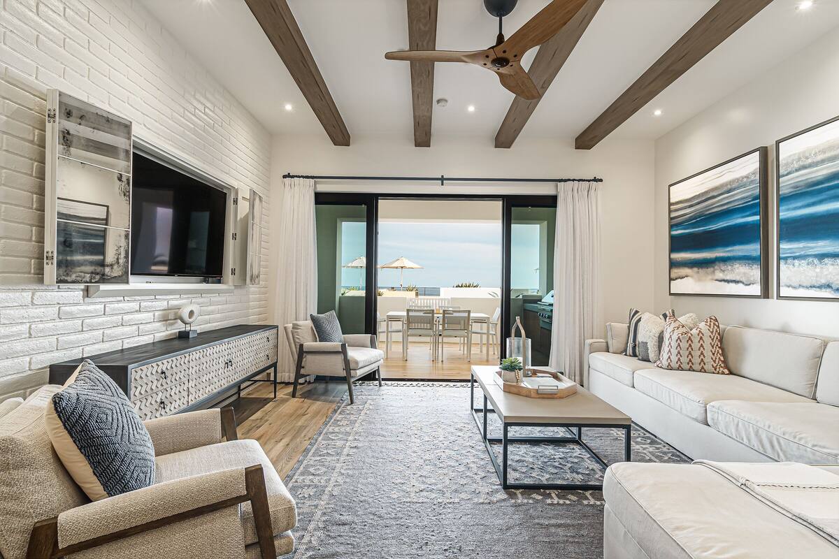 A modern living room with a fireplace, a large TV, and a dining area with a view.