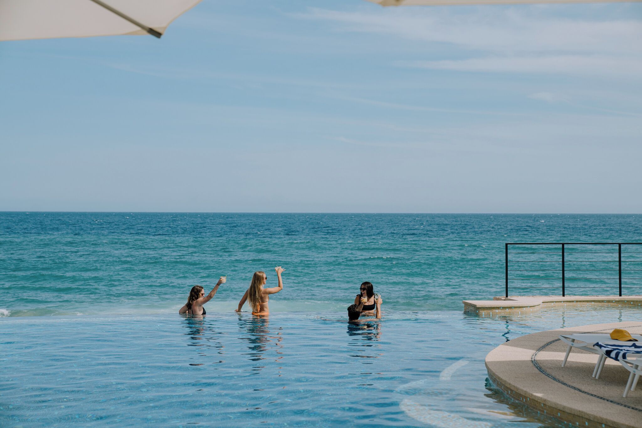 A poolside area with a lounge chair and a table, overlooking a body of water.