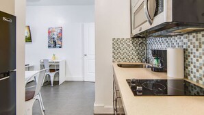 A modern kitchen with a microwave, stove, and sink. There is a dining area with a table and chairs.