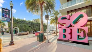 A street with a large pink sign that reads "SO BE" and a building with a balcony in the background. - Comfy 1 B/R, Near Ocean Dr & Beach - South Beach (Miami Beach)