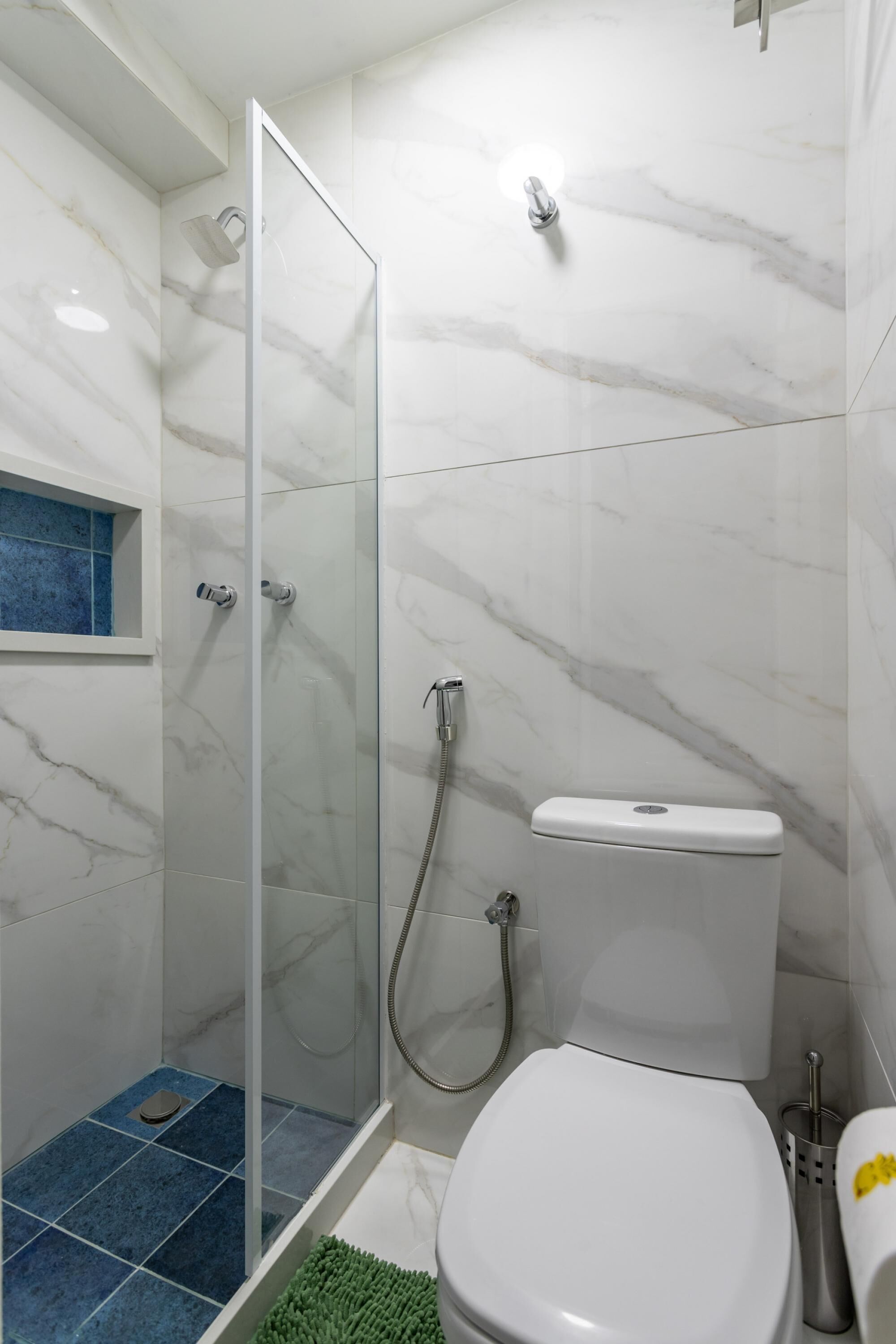 A bathroom with a glass-enclosed shower, a toilet, and a blue-tiled floor.