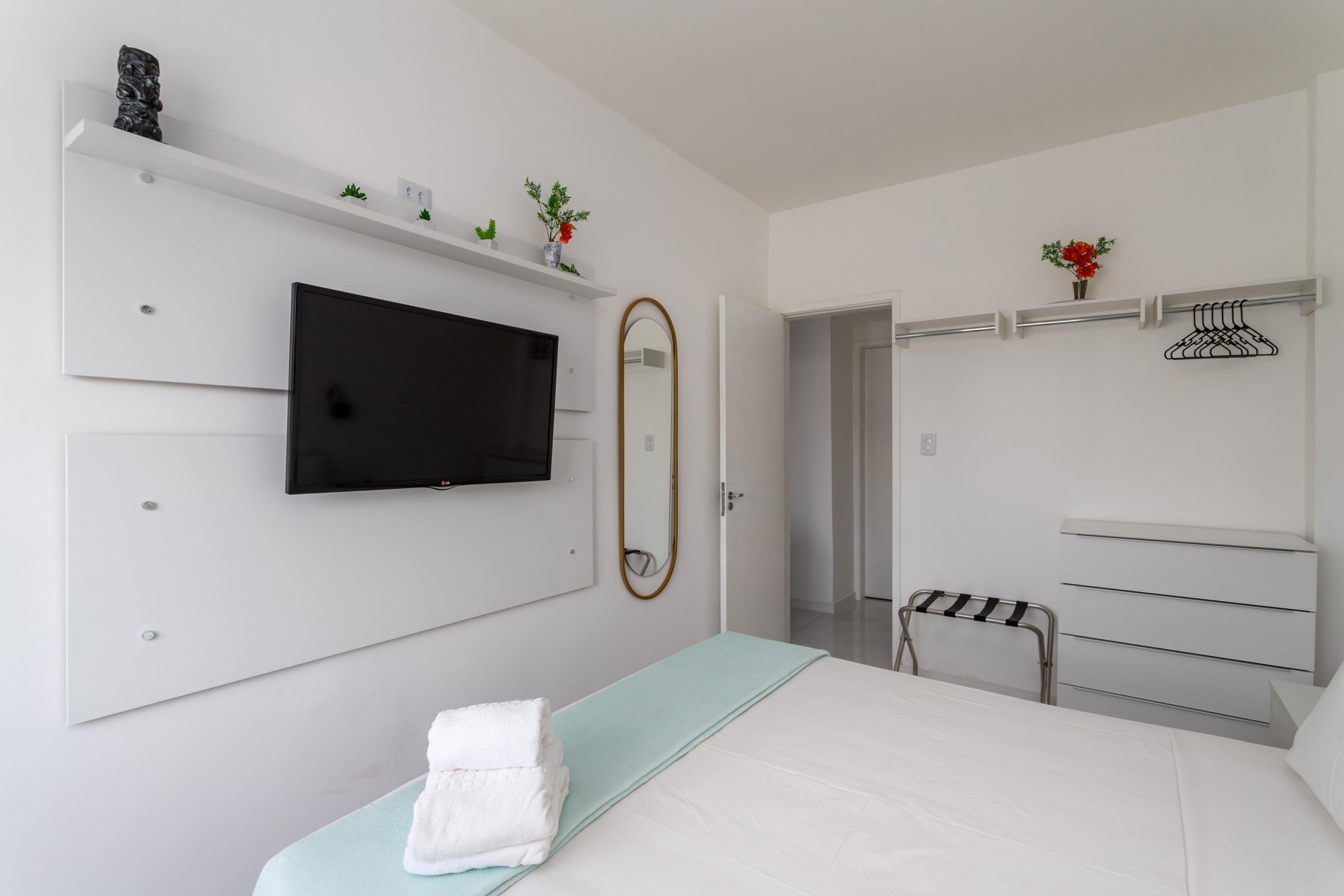 Une chambre moderne comprenant un lit, une télévision, un miroir, une armoire et un espace douche.