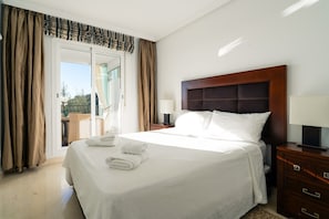 A hotel room with a bed, a nightstand, a lamp, and a view of the outdoors through a sliding door. - El Bosque de la Mairena (Ojen)