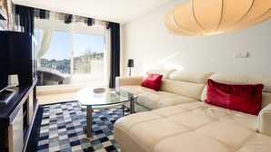 Un salón moderno con una mesa de centro de vidrio, sofá color beige y un ventanal con vistas.