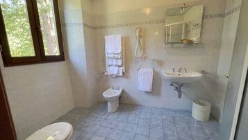 A bathroom with a toilet, bidet, sink, and a shower.