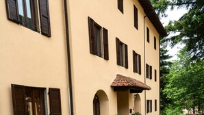 A building with a beige facade, multiple windows with dark shutters, and a tiled roof. - Hotel Rifugio la Foresta  (Reggello)