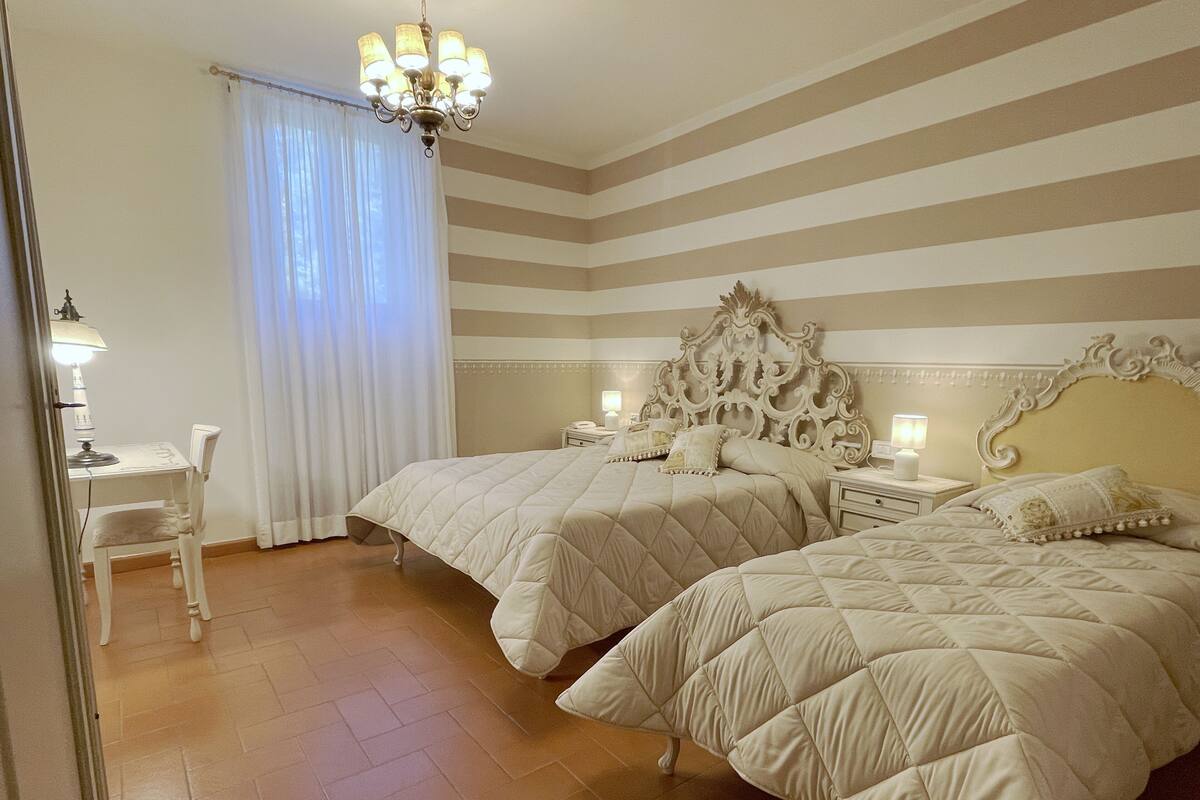 Une chambre d’hôtel avec deux lits, un bureau, une chaise et un lustre.