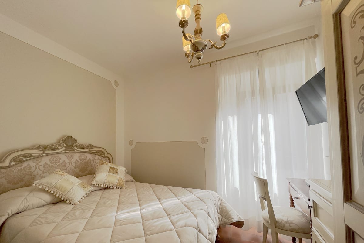Une chambre à coucher avec un grand lit, une chaise, un bureau et un lustre.
