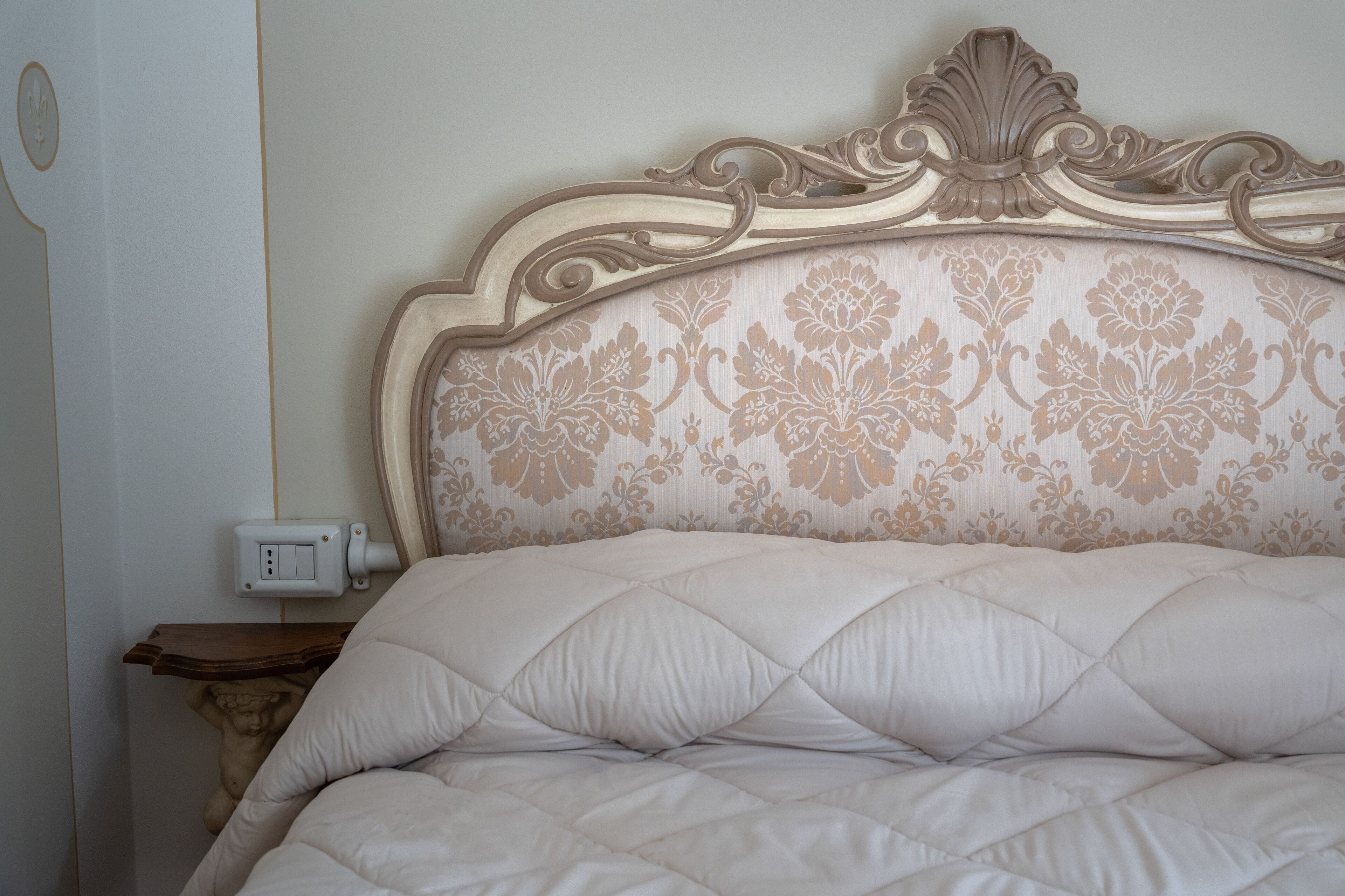 Una cama con cabecera decorativa y edredón acolchado.