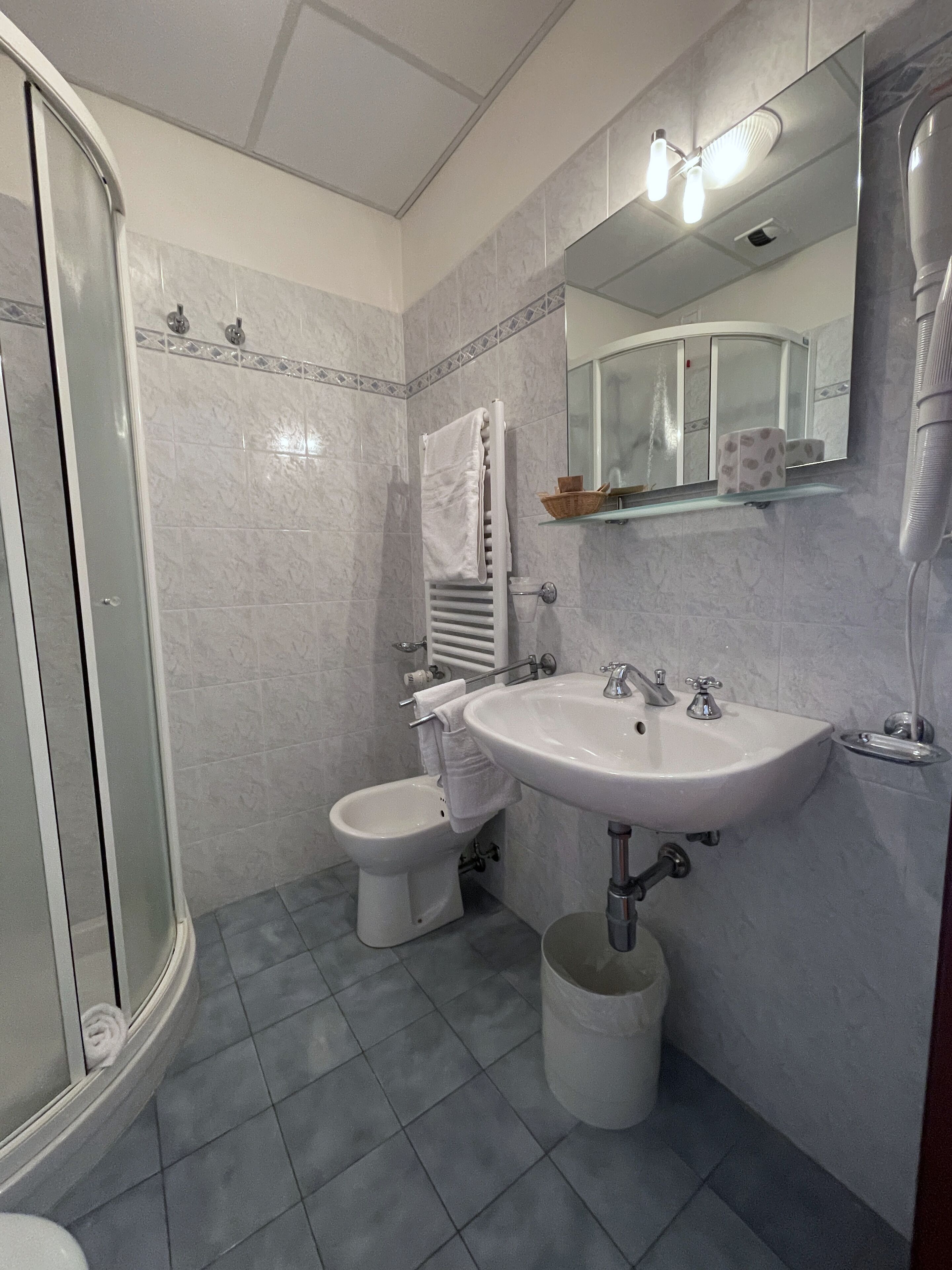 Un baño con ducha, inodoro, bidé, lavamanos y espejo.