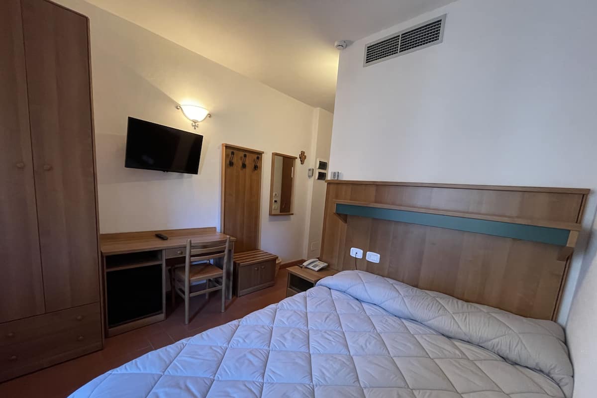 Une chambre d’hôtel comprenant un lit, un bureau avec une chaise, une télévision, une armoire et un miroir.