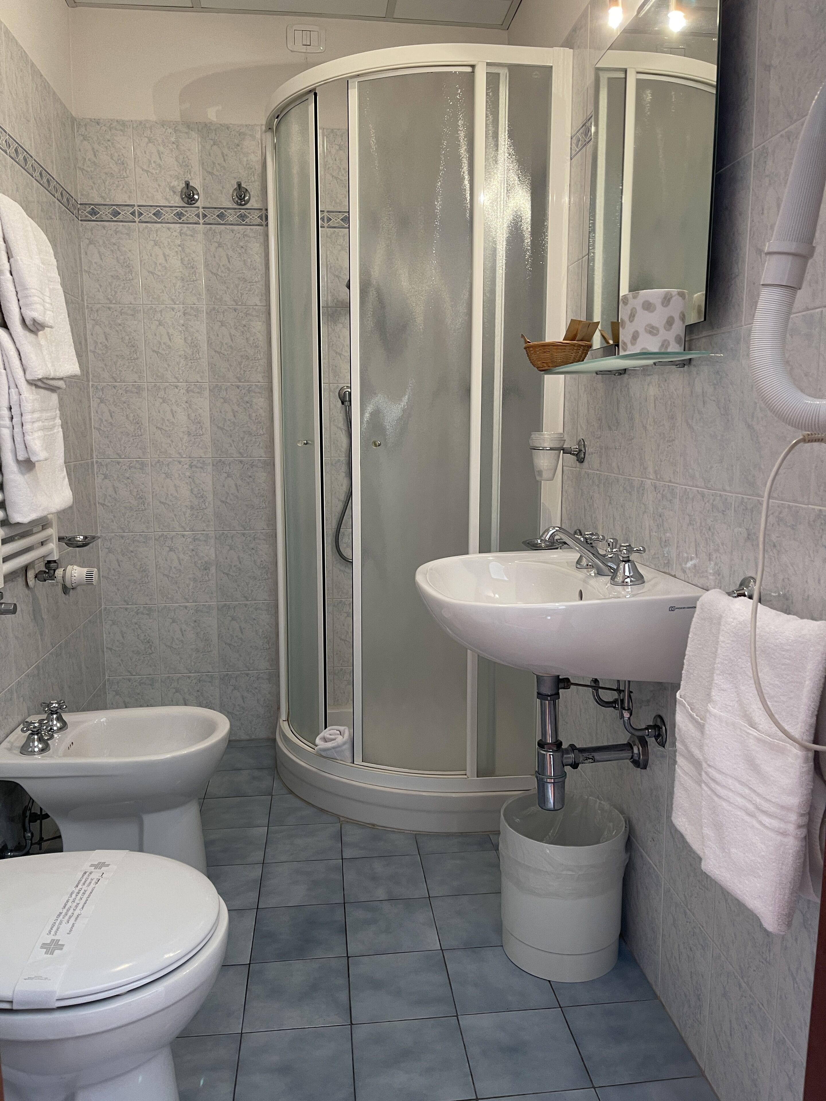 Un baño con ducha, inodoro, bidé, lavamanos y toallero.