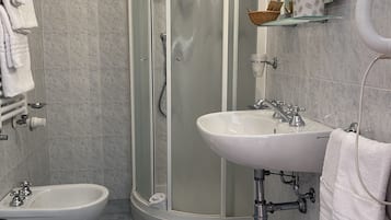 Un baño con ducha, inodoro, bidé, lavamanos y toallero.