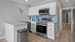 Una cocina moderna con armarios blancos, electrodomésticos de acero inoxidable y un salpicadero azul.
